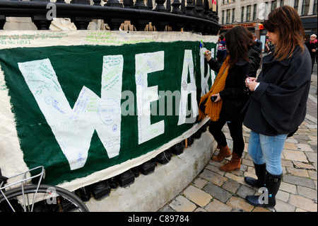 Protesters make comments on the large ‘WE ARE THE 99%’ poster - Occupy London Stock Exchange OLX is part of a global movement against corporate greed in the face of bank bailouts, unemployment, inequality and austerity measures. City of London, UK. Stock Photo