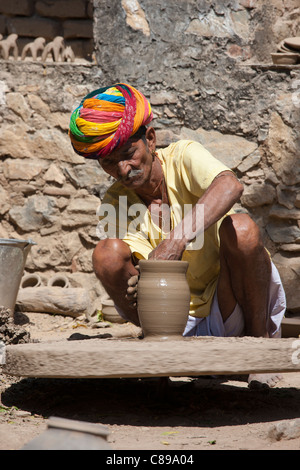 Indian potter in Rajasthani turban works potter's wheel at home making clay pots in Nimaj village, Rajasthan, India Stock Photo
