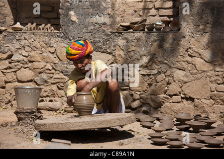 Potter in traditional Rajasthani turban works on potter's wheel at home making clay pots in Nimaj village, Rajasthan, India Stock Photo