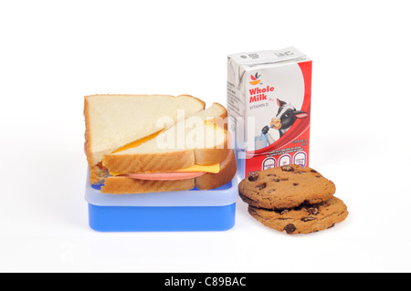 Bologna and cheese sandwich on white bread on top of lunch box with carton of milk and cookies on white background. Stock Photo