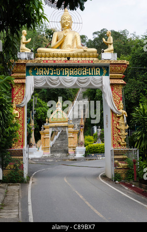 Large entrance arch with a gold Buddha sculpture on top over road at Wat Doi Saket in northern Thailand Stock Photo
