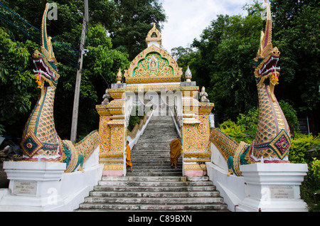 Novice Buddhist monks at staircase entrance with large naga heads and archway at Wat Doi Saket in northern Thailand Stock Photo