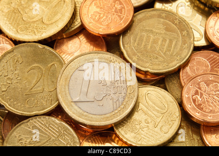 A one Euro denomination coin sits near the center of a pile of other current, modern, Euro coins. Stock Photo