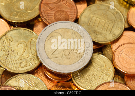 A two Euro denomination coin sits near the center of a pile of other current, modern, Euro coins. Stock Photo