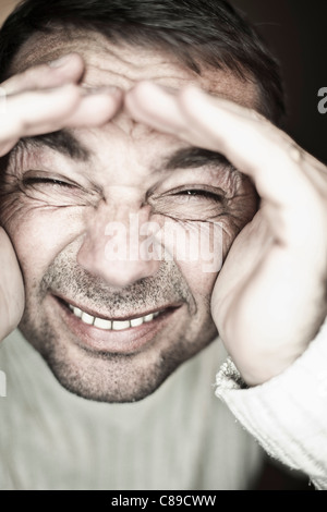 Close up of mature man making funny faces against black background, smiling Stock Photo