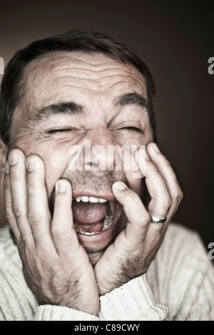Close up of mature man making funny faces against black background Stock Photo