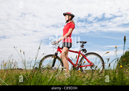 Germany, Bavaria, Young woman walking with mountain bike Stock Photo