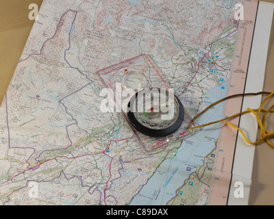 Ordnance survey map of the area of Coniston in the English Lake District with a hiker's compass on a table. Stock Photo