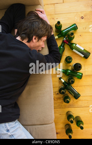 Germany, Hessen, Frankfurt, Drunk man lying on sofa with empty beer bottles Stock Photo