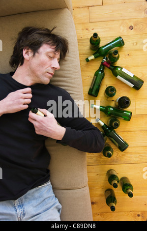 Germany, Hessen, Frankfurt, Drunk man lying on sofa with empty beer bottles Stock Photo