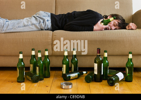 Germany, Hessen, Frankfurt, Drunk man lying on sofa with empty beer bottles Stock Photo