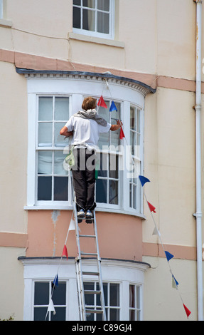 Window cleaner cleaning windows at property in Weymouth in July Stock Photo