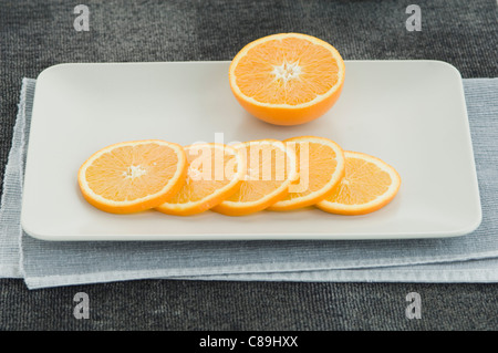 Half orange with slices on plate, close up Stock Photo