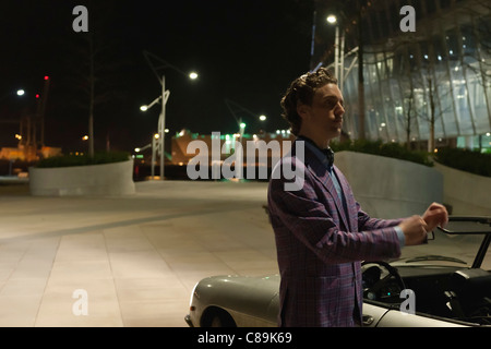 Germany, Hamburg, Man standing beside classic cabriolet car at night Stock Photo