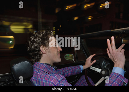 Germany, Hamburg, Man driving classic cabriolet car at night Stock Photo