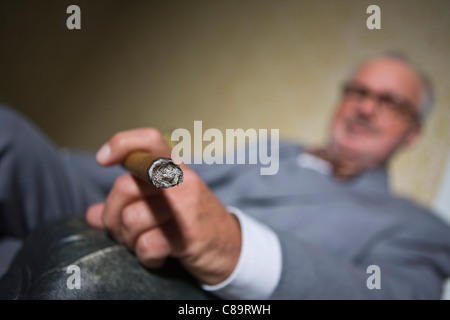 Germany, Braunschweig, Senior man smoking cigar, close up Stock Photo