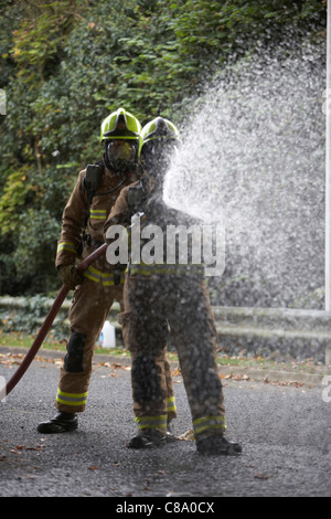 Firefighters with a hose wearing breathing apparatus, UK Stock Photo