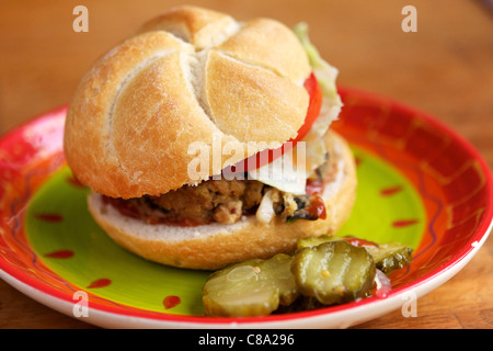 A vegan burger made from eggplants, onions and bread crumbs, served on a bun with lettuce and tomatoes and sweet pickle chips. Stock Photo