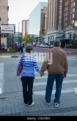 Grand Rapids, Michigan - A middle-aged couple holds hands while waiting to cross a downtown street. Stock Photo