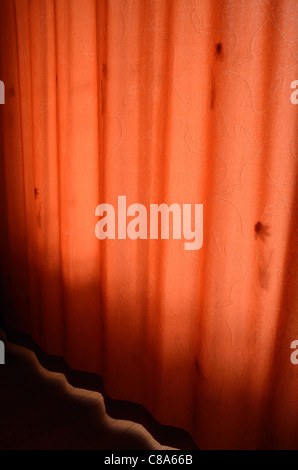 Red curtain hanging in bedroom window Stock Photo