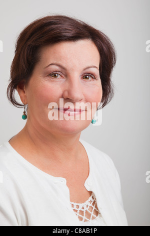 Portrait of a beautiful middle aged woman against a gray background. Stock Photo