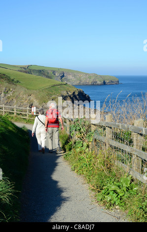 an elderly couple walking on the south west coast footpath at port isaac in north cornwall, uk Stock Photo