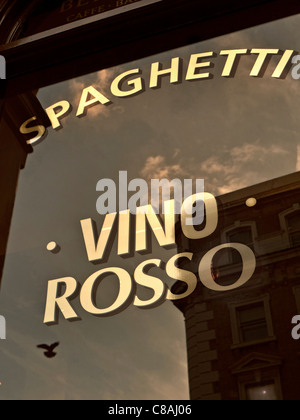 Sign on window of Italian wine bar at sunset promoting Spaghetti and Vino Rosso Stock Photo