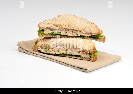 Tuna mayo sandwich with lettuce made with wholemeal bread cut in half and stacked on white background, cutout. Stock Photo