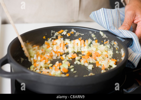 Stirring the diced carrots and celery in a frying pan