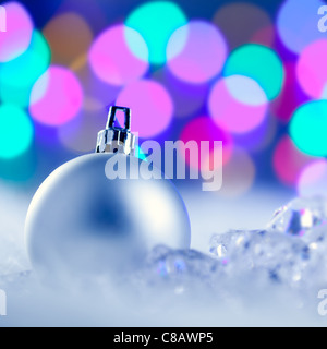 Christmas silver bauble in colorful blurred lights background Stock Photo