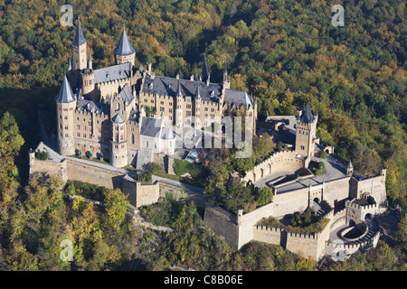 AERIAL VIEW. Castle on a forested hill with autumnal colors. Hohenzollern Castle, Hechingen, Baden-Wurttemberg, Germany. Stock Photo