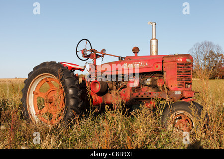 An old, red Farmall tractor sitting in a field, northern Minnesota. Stock Photo