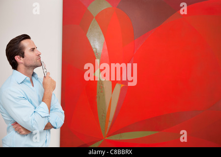 Thoughtful young man looking at painting in art gallery Stock Photo