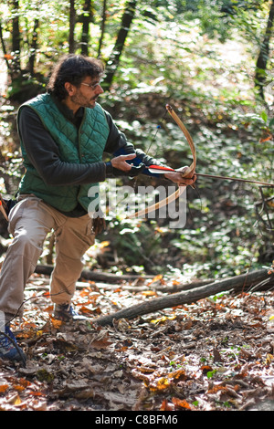 longbow man practicing archery in a forest Stock Photo