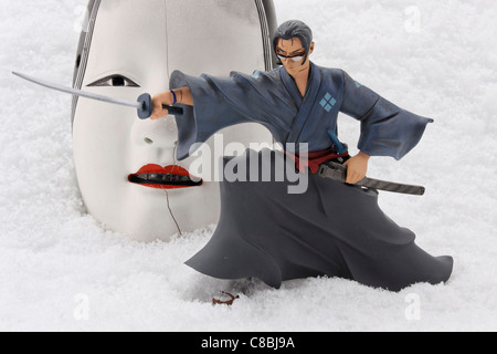 figurine of samurai jin fighting in front of traditional noh theatre mask of ko-omote - editorial use only Stock Photo