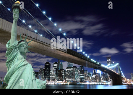 Manhattan Skyline, Brooklyn Bridge and The Statue of Liberty at Night Lights, New York City Stock Photo