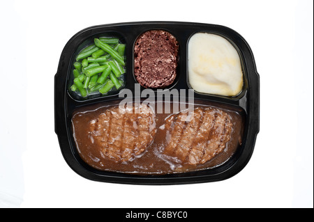 An unhealthy Salisbury steak TV dinner with gravy, mashed potatoes and a brownie dessert in a plastic tray isolated on white Stock Photo