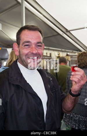 Portrait of a man smiling at a camera and holding a cider sample to taste at the local Cornish food and drink festival in Truro Stock Photo