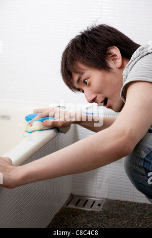 Young man scrubbing bathtub Stock Photo