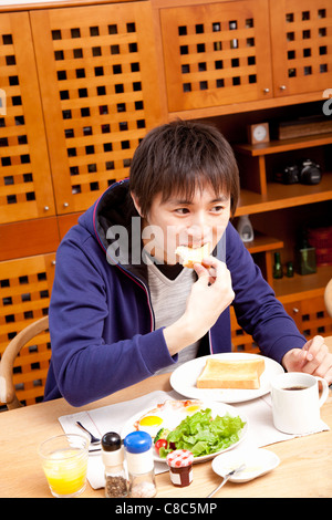 Young man eating breakfast Stock Photo