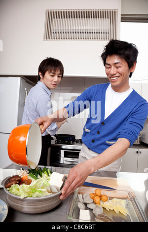 Two men cooking together in the kitchen Stock Photo