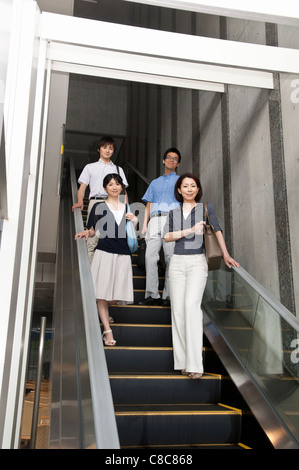 Businessmen and businesswomen in business casual getting on escalator Stock Photo