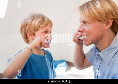 Father and son brushing their teeth Stock Photo