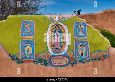 Our Lady of Guadalupe mural at adobe wall at house in Santa Cruz, New Mexico, USA Stock Photo