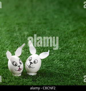 "bunny styled" easter eggs in green artificial grass background Stock Photo