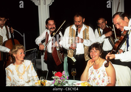 Budapest, Hungary. Traditional Hungarian gypsy band playing for guests at a restaurant; violin, cello, clarinet. Stock Photo