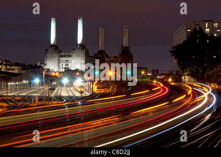 Battersea power station at night with light trails left by the trains approaching and departing from Victoria train station Stock Photo