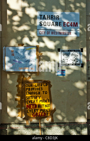 St Pauls, London, anti capitalist camp. Posters on wall 'Tahrir Square' and 'This world provides enough for every man's need...' Stock Photo