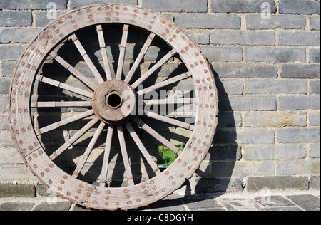 Old carriage wheel against  brick wall Stock Photo