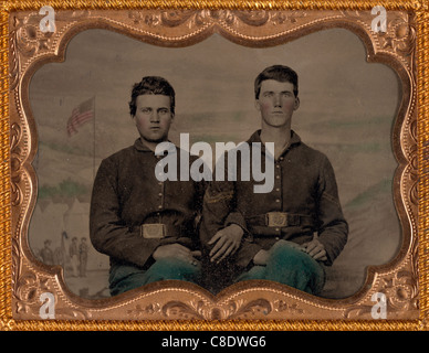 Two unidentified soldiers in Union uniforms in front of painted backdrop showing military camp scene - USA Civil War Stock Photo